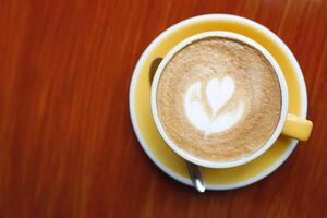 hot coffee cup latte art with spoon Serve ready to drink in cafe on wooden table coffee shop. Leave copy space empty to write the side text. soft focus. photo
