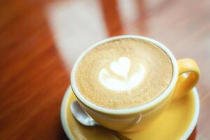 hot coffee cup latte art with spoon Serve ready to drink in cafe on wooden table coffee shop. Leave copy space empty to write the side text. soft focus. photo