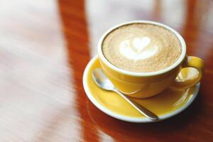 hot coffee cup latte art with spoon Serve ready to drink in cafe on wooden table coffee shop. Leave copy space empty to write the side text. soft focus. photo