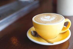 hot coffee cup latte art with spoon Serve ready to drink in cafe on wooden table coffee shop. Leave copy space empty to write the side text. soft focus. photo