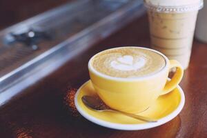 hot coffee cup latte art with spoon Serve ready to drink in cafe on wooden table coffee shop. Leave copy space empty to write the side text. soft focus. photo