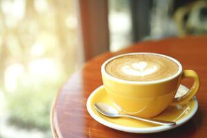 hot coffee cup latte art with spoon Serve ready to drink in cafe on wooden table coffee shop. Leave copy space empty to write the side text. soft focus. photo