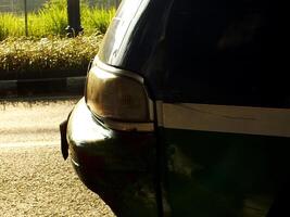 View from side of a car with a green stripe and white on the side. Close up selective focus head lamp photo
