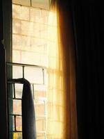 View from inside room, looking outside through A window with a curtain drawn. There is sunlight passing it creating calm and loneliness ambience photo