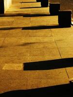 Morning walk at a sidewalk with a row of pillars and a shadow cast on the ground photo