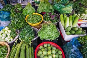 Various vegetables and herbs on the market in wicker baskets. photo