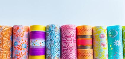 Colorful rolls of patterned fabric in a row against a clear sky. Concept of textile designs, fabric patterns, arts and crafts, colorful materials photo