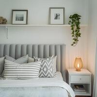 Bedroom with plush headboard, pillows, and a shelf with plant and pictures For Social Media Post Size photo