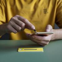Person in a yellow shirt holds a smartphone and a small tool For Social Media Post Size photo