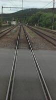 View of railway tracks captured from a moving train. The image emphasizes the motion and forward direction, ideal for illustrating travel, transportation, or journey themes video