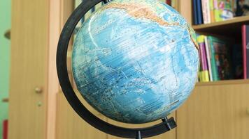 Close-up of a globe standing on a desk with bookcases in the background. Minsk, Belarus - July 7, 2024 video