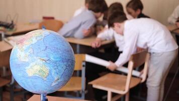School boys are discussing something. There is a globe in the background. Minsk, Belarus - May 10, 2024 video