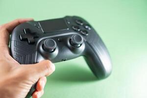 A person holding a black game controller on a green background photo