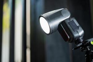 A flash light is on a tripod in front of a window photo