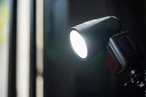 A flash light is on a tripod in front of a window photo