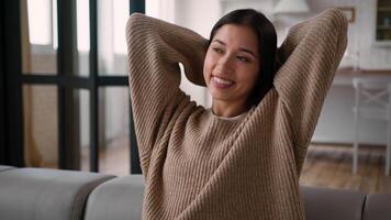 Caucasian Hispanic woman satisfied girl female homeowner sit on sofa home comfort relax happy smiling lady put hands behind head relaxation enjoy lazy casual weekend leisure rest alone air conditioner video
