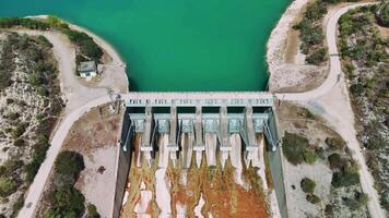 Aerial views showcase a dam gradually releasing water, decreasing the reservoir's water level and revealing the bottom. The scene highlights the interplay between infrastructure and nature video