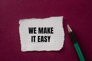 We make it easy text on a piece of paper with a pen on a red background photo