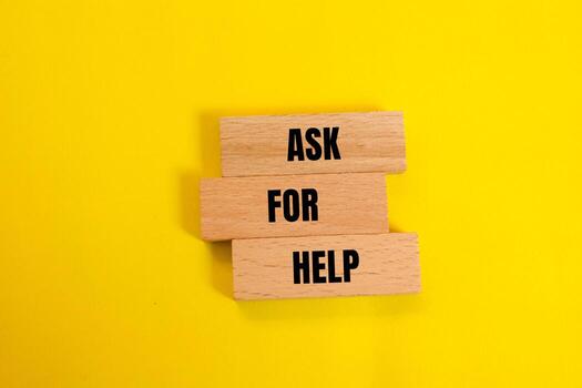 Ask for help message written on wooden blocks with yellow background. Conceptual ask for help symbol. Copy space. photo