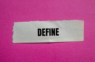 Define message written on ripped torn paper piece with pink background. Conceptual define symbol. Copy space. photo