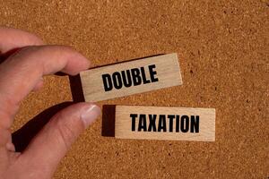 Double taxation message written on wooden blocks with brown background. Conceptual double taxation symbol. Copy space. photo