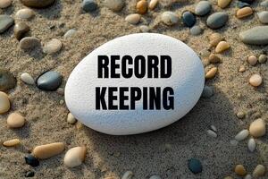 Record keeping message written on white stone on beach sands. Conceptual record keeping symbol. Copy space. photo