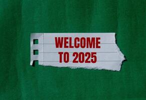 Welcome to 2025 message written on ripped torn paper with green background. Conceptual welcome to 2025 symbol. Copy space. photo