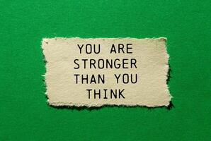 You are stronger than you think message written on ripped torn paper piece on green background. Conceptual you are stronger than you think symbol. Copy space. photo