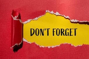 Don't forget message written on ripped torn red paper with yellow background. Conceptual don't forget symbol. Copy space. photo