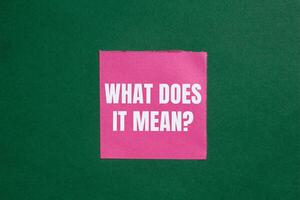 What does it mean question written on ripped torn pink paper on green background. Conceptual what does it mean question symbol. Copy space. photo