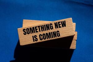 Something new is coming message written on wooden blocks on blue background. Conceptual something new is coming symbol. Copy space. photo