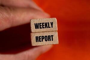 Weekly report message written on wooden blocks with orange background. Conceptual weekly report symbol. Copy space. photo