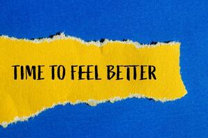 Time to feel better message written on ripped torn yellow paper with blue background. Conceptual time to feel better symbol. Copy space. photo