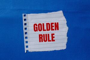 Golden rule text on a piece of paper on a blue background photo
