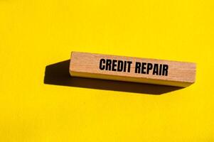 Credit repair message written on wooden block with yellow background. Conceptual credit repair symbol. Copy space. photo
