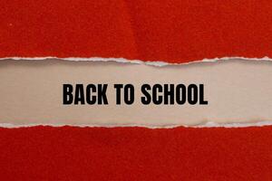 Back to school message written on ripped red torn paper with beige background. Conceptual back to school symbol. Copy space. photo