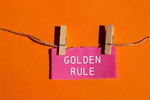 Golden rule message written on ripped torn pink paper piece with orange background. Conceptual golden rule symbol. Copy space. photo