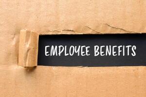 Employee benefits message written on ripped torn cardboard paper with black background. Conceptual employee benefits symbol. Copy space. photo
