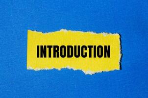 Introduction message written on ripped yellow torn paper piece with blue background. Conceptual introduction symbol. Copy space. photo