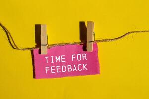 Time for feedback words written on ripped pink paper piece with yellow background. Conceptual time for feedback symbol. Copy space. photo