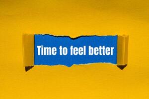 Time to feel better message written on ripped torn yellow paper with blue background. Conceptual time to feel better symbol. Copy space. photo