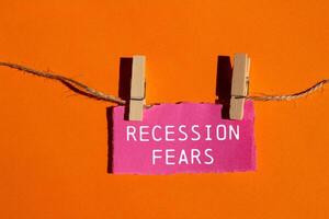 Recession fears message written on ripped pink torn paper piece on orange background. Conceptual recession fears symbol. Copy space. photo