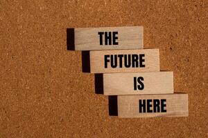 The future is here message written on wooden blocks on brown background. Conceptual the future is here symbol. Copy space. photo