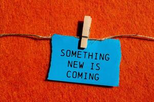Something new is coming message written on ripped blue torn paper piece on orange background. Conceptual something new is coming symbol. Copy space. photo