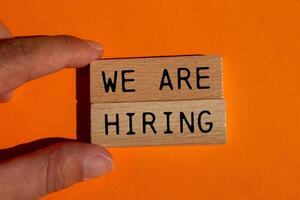 We are hiring message written on wooden blocks on orange background. Conceptual we are hiring symbol. Copy space. photo