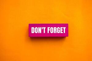 Don't forget message written on pink wooden block with orange background. Conceptual don't forget symbol. Copy space. photo