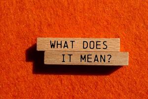 What does it mean question written on wooden blocks on orange felt background. Conceptual what does it mean question symbol. Copy space. photo