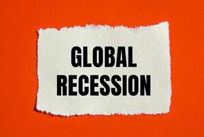 Global recession message written on ripped torn paper piece with orange background. Conceptual global recession symbol. Copy space. photo