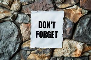 Don't forget message written on ripped white torn paper with stone background. Conceptual don't forget symbol. Copy space. photo