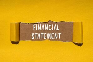 Financial statement message written on ripped torn yellow paper with brown background. Conceptual financial statement symbol. Copy space. photo